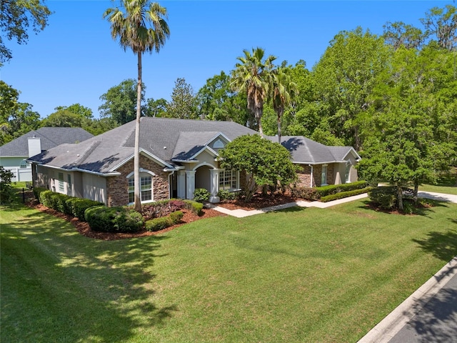 ranch-style home featuring a front lawn and stone siding