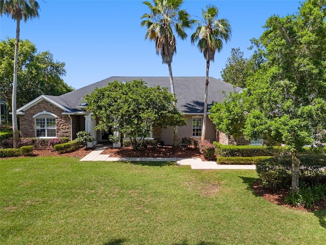 obstructed view of property featuring stone siding, a front lawn, and a shingled roof