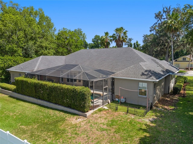 rear view of house featuring roof with shingles, glass enclosure, and stucco siding
