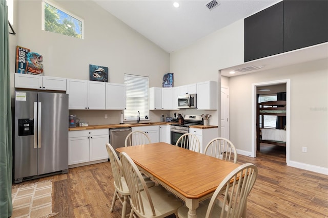 754 SE 167th Court Rd, Silver Springs, FL 34488 - kitchen with appliances with stainless steel finishes, high vaulted ceiling, a sink, light wood-type flooring, and white cabinetry