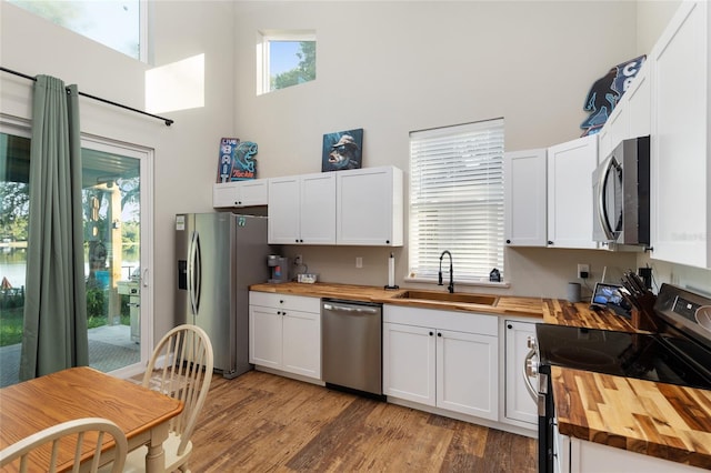 754 SE 167th Court Rd, Silver Springs, FL 34488 - kitchen with wooden counters, appliances with stainless steel finishes, a towering ceiling, a sink, and light wood-type flooring