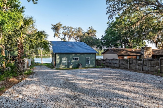 754 SE 167th Court Rd, Silver Springs, FL 34488 - rear view of house with fence, metal roof, driveway, and a water view