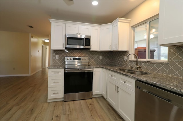 6472 SW 106th Pl, Ocala, FL 34476 - kitchen with stainless steel appliances, a sink, light wood finished floors, white cabinets, and recessed lighting