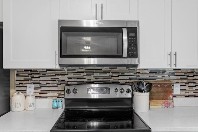 729 Sinclair Ter, Inverness, FL 34450 - kitchen view of appliances with stainless steel finishes, white cabinetry, decorative backsplash, and light stone countertops
