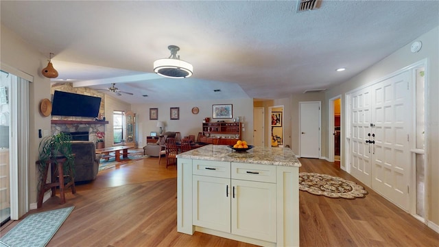 307 N Kinglet Ave, Hernando, FL 34442 - kitchen featuring light wood-style floors, a stone fireplace, open floor plan, ceiling fan, and a kitchen island
