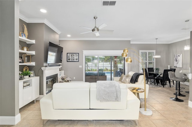 3612 SE 47th Ter, Ocala, FL 34480 - living room featuring ceiling fan, a glass covered fireplace, crown molding, light tile patterned flooring, and recessed lighting