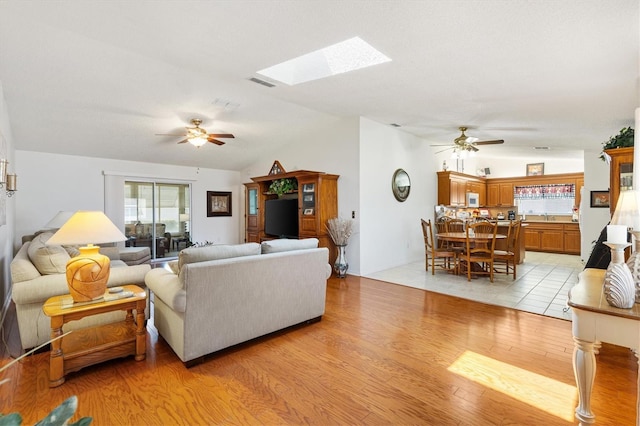17576 SE 96th Ct, Summerfield, FL 34491 - living room featuring a ceiling fan, lofted ceiling, light wood-style flooring, and a skylight