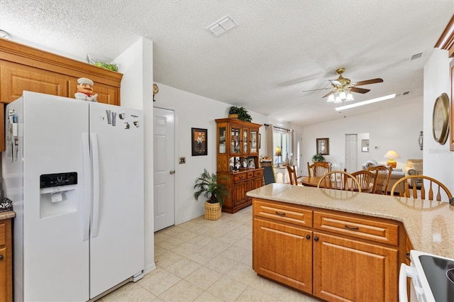 17576 SE 96th Ct, Summerfield, FL 34491 - kitchen with white appliances, a ceiling fan, light tile patterned flooring, brown cabinetry, and a textured ceiling