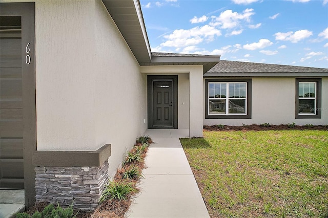 20 Emerald Trl, Ocala, FL 34472 - view of exterior entry featuring stucco siding, a lawn, stone siding, and a shingled roof