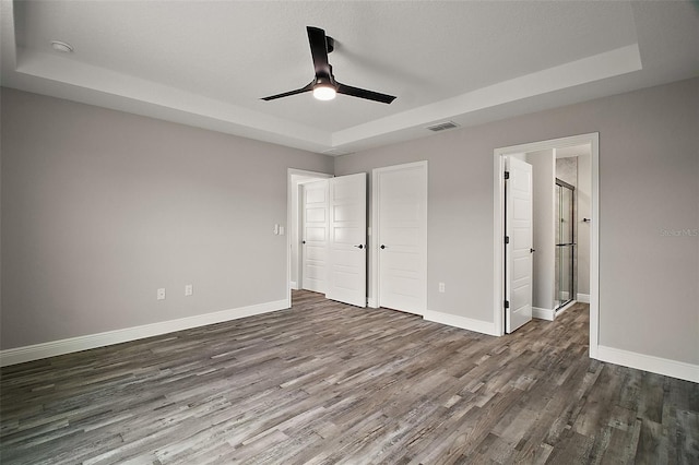 20 Emerald Trl, Ocala, FL 34472 - unfurnished bedroom with a tray ceiling, dark wood-style flooring, and baseboards