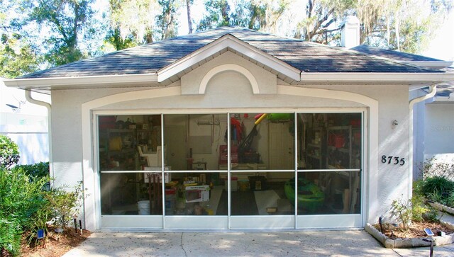 8735 SW 192nd Court Rd, Dunnellon, FL 34432 - view of side of home featuring roof with shingles, a chimney, and stucco siding