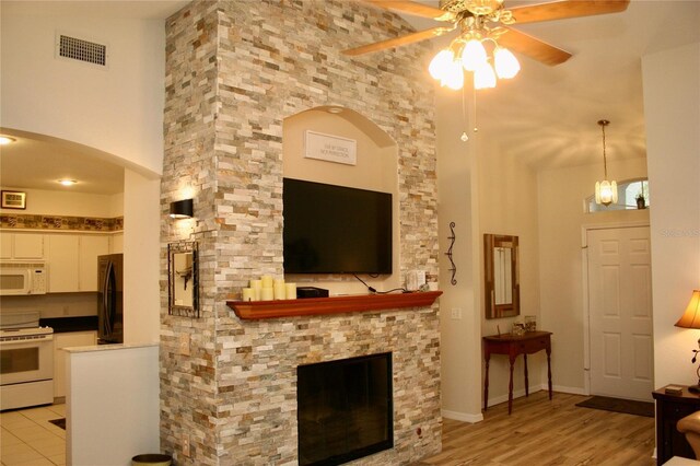 8735 SW 192nd Court Rd, Dunnellon, FL 34432 - living area featuring ceiling fan, arched walkways, a towering ceiling, light wood-style floors, and a stone fireplace