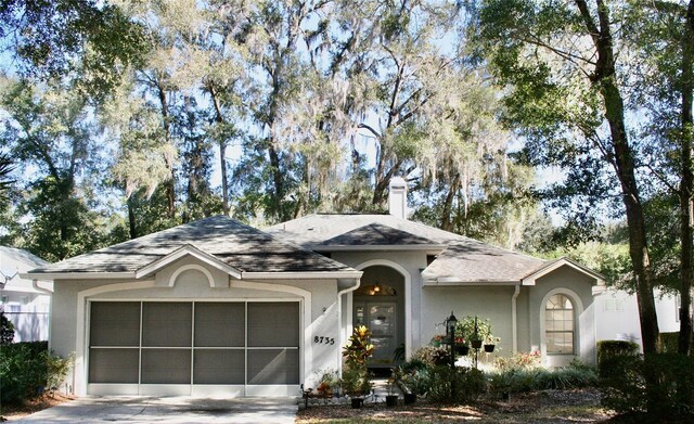 8735 SW 192nd Court Rd, Dunnellon, FL 34432 - ranch-style house featuring an attached garage, driveway, a chimney, stucco siding, and roof with shingles