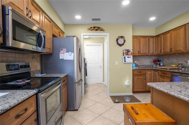 4692 N Lake Vista Trl, Hernando, FL 34442 - kitchen featuring stainless steel appliances, light tile patterned floors, brown cabinetry, tasteful backsplash, and recessed lighting