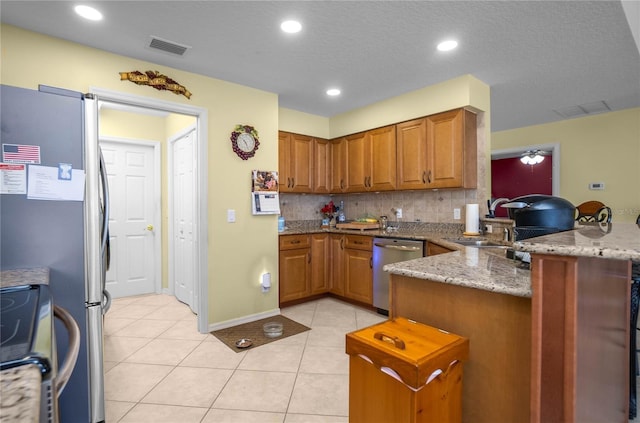 4692 N Lake Vista Trl, Hernando, FL 34442 - kitchen featuring appliances with stainless steel finishes, a peninsula, brown cabinets, light stone counters, and recessed lighting