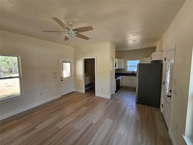 13391 NE 51st St, Williston, FL 32696 - unfurnished living room featuring wood finished floors, ceiling fan, baseboards, a sink, and a textured ceiling