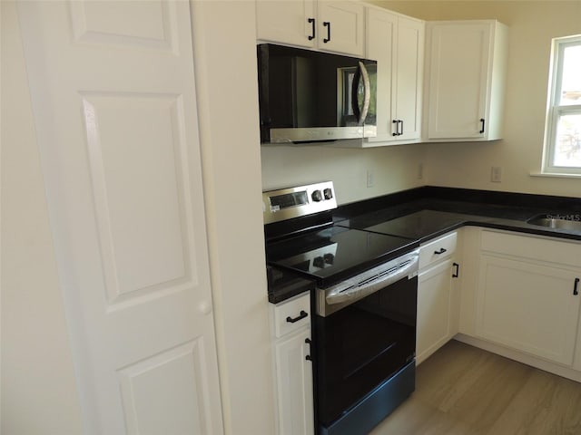 13391 NE 51st St, Williston, FL 32696 - kitchen featuring stainless steel electric range oven, dark countertops, white cabinets, and light wood-type flooring
