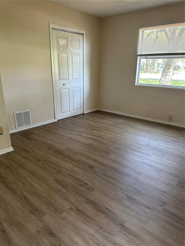 312 NW 28th St, Ocala, FL 34475 - unfurnished bedroom featuring wood finished floors, baseboards, a closet, and a textured ceiling