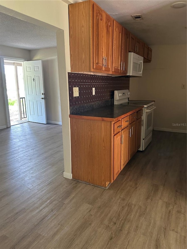 312 NW 28th St, Ocala, FL 34475 - kitchen featuring white appliances, dark countertops, tasteful backsplash, wood finished floors, and baseboards