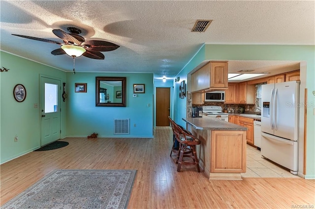5626 W Justin Ct, Homosassa, FL 34448 - kitchen with white appliances, a sink, light wood-style floors, a kitchen breakfast bar, and a textured ceiling