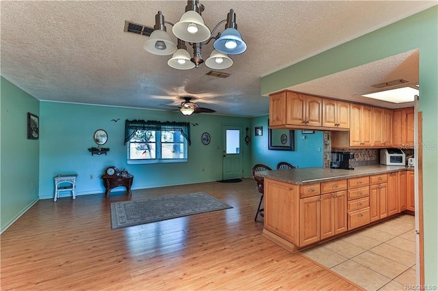 5626 W Justin Ct, Homosassa, FL 34448 - kitchen featuring a textured ceiling, open floor plan, a chandelier, light wood-style flooring, and a breakfast bar