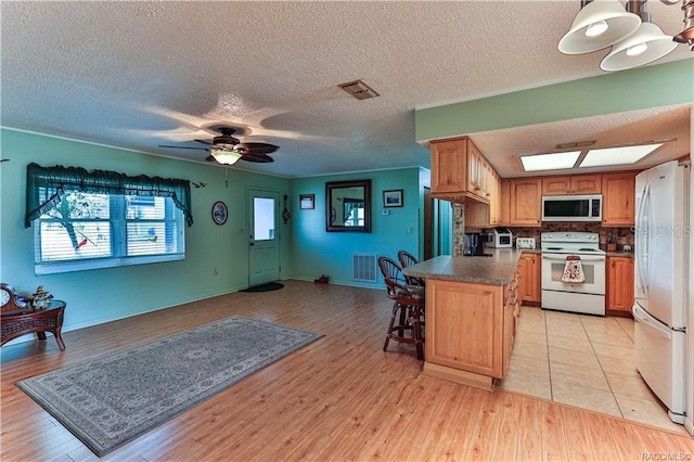 5626 W Justin Ct, Homosassa, FL 34448 - kitchen featuring white electric range, freestanding refrigerator, a kitchen bar, dark countertops, and a textured ceiling