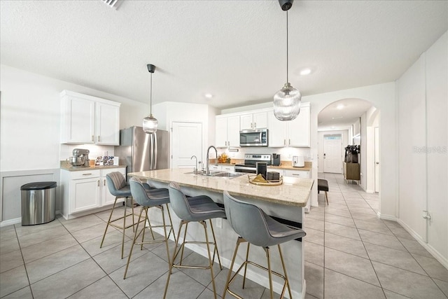 160 Hickory Course Loop, Ocala, FL 34472 - kitchen featuring stainless steel appliances, arched walkways, light tile patterned floors, white cabinets, and a breakfast bar