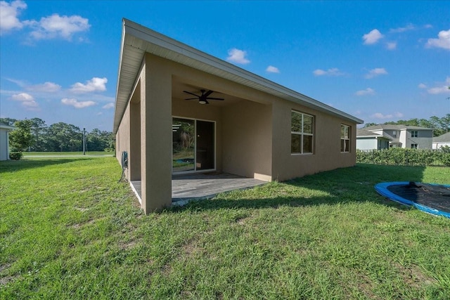 160 Hickory Course Loop, Ocala, FL 34472 - back of house with a ceiling fan, stucco siding, a yard, and a trampoline