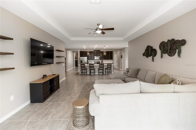 5248 Red Coral Cir, Mount Dora, FL 32757 - living room featuring ceiling fan, baseboards, a tray ceiling, and light tile patterned flooring