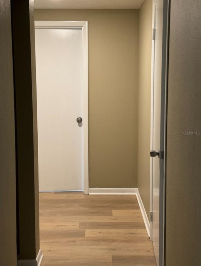 hall with light wood finished floors and baseboards