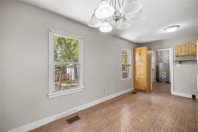 1014 NE 12th St, Ocala, FL 34470 - unfurnished dining area featuring water heater, baseboards, wood finished floors, a chandelier, and a textured ceiling