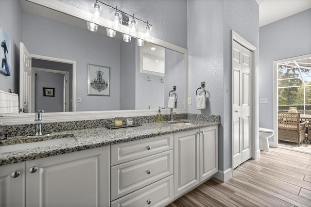1107 SE 49th Ave, Ocala, FL 34471 - bathroom with a textured wall, double vanity, toilet, wood finished floors, and baseboards