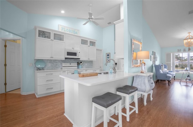 3656 E Lake Todd Dr, Hernando, FL 34442 - kitchen featuring white appliances, high vaulted ceiling, a sink, a breakfast bar area, and light wood-style floors