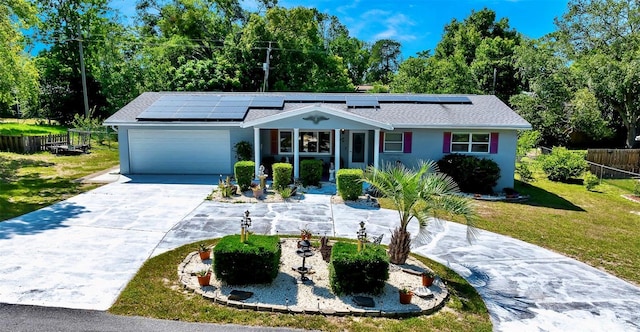 66 S Desoto St, Beverly Hills, FL 34465 - view of front facade featuring driveway, a garage, roof mounted solar panels, and view of scattered trees