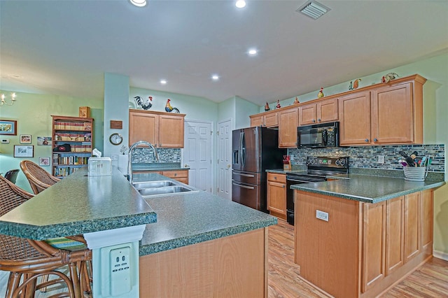 14004 SE 94th Ave, Summerfield, FL 34491 - kitchen featuring a sink, black appliances, light wood-style flooring, backsplash, and a peninsula