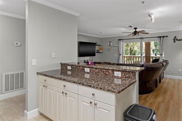 4450 E Windmill Dr Unit 101, Inverness, FL 34453 - kitchen featuring a peninsula, baseboards, ceiling fan, ornamental molding, and white cabinetry
