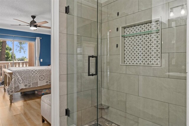 4450 E Windmill Dr Unit 101, Inverness, FL 34453 - ensuite bathroom featuring a shower stall, a ceiling fan, wood finished floors, and a textured ceiling
