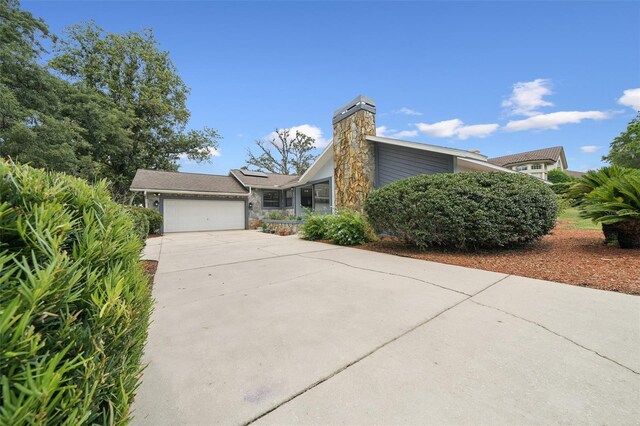 451 E Ireland Ct, Hernando, FL 34442 - view of front of home with driveway, a garage, a chimney, and solar panels