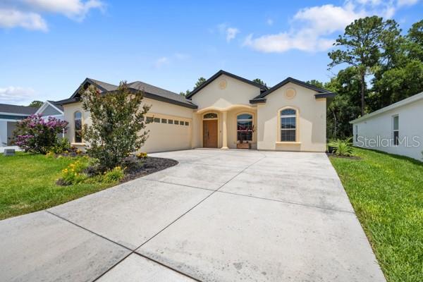 6235 SW 95th Pl, Ocala, FL 34476 - view of front of property featuring a garage, driveway, stucco siding, and a front lawn