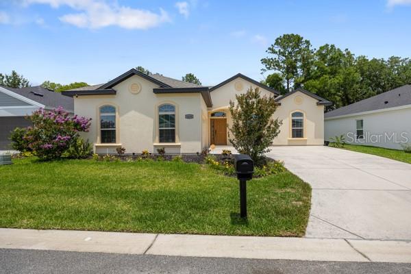 6235 SW 95th Pl, Ocala, FL 34476 - view of front facade with driveway, stucco siding, and a front lawn