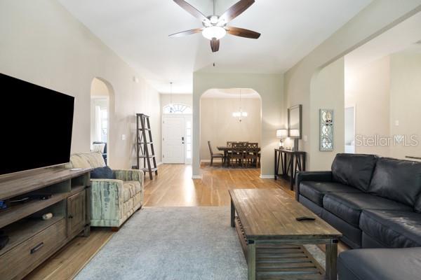 6235 SW 95th Pl, Ocala, FL 34476 - living area with arched walkways, ceiling fan, light wood-style floors, and a chandelier