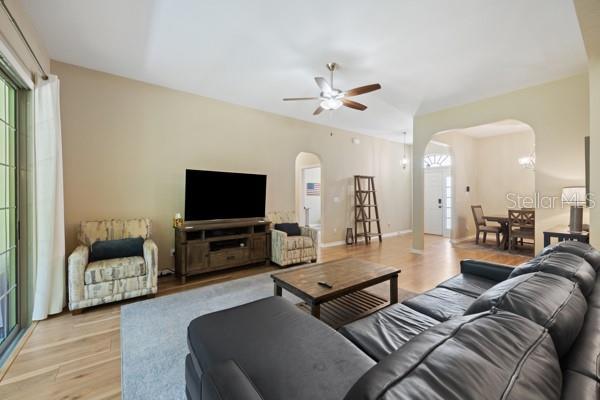 6235 SW 95th Pl, Ocala, FL 34476 - living room featuring arched walkways, a ceiling fan, and light wood finished floors