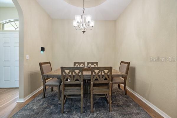 6235 SW 95th Pl, Ocala, FL 34476 - dining room featuring arched walkways, wood finished floors, a chandelier, and baseboards