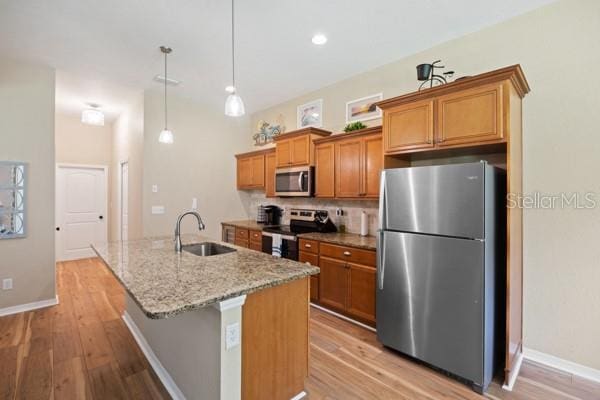 6235 SW 95th Pl, Ocala, FL 34476 - kitchen with stainless steel appliances, a sink, brown cabinetry, light wood-style flooring, and recessed lighting