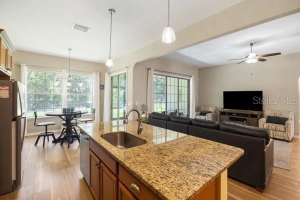 6235 SW 95th Pl, Ocala, FL 34476 - kitchen featuring a sink, appliances with stainless steel finishes, brown cabinets, light wood finished floors, and an island with sink