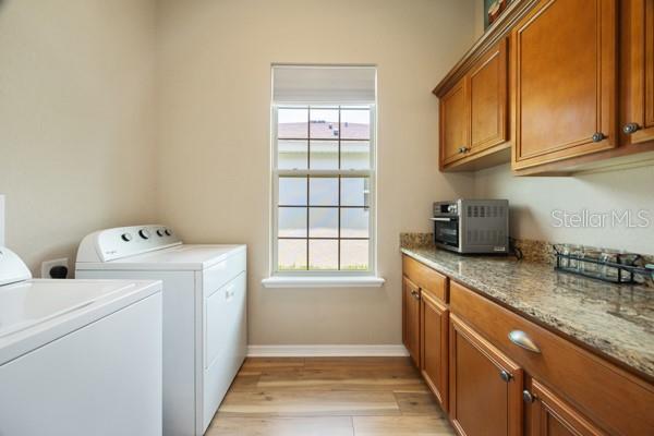 6235 SW 95th Pl, Ocala, FL 34476 - laundry room featuring cabinet space, independent washer and dryer, light wood-style flooring, and healthy amount of natural light