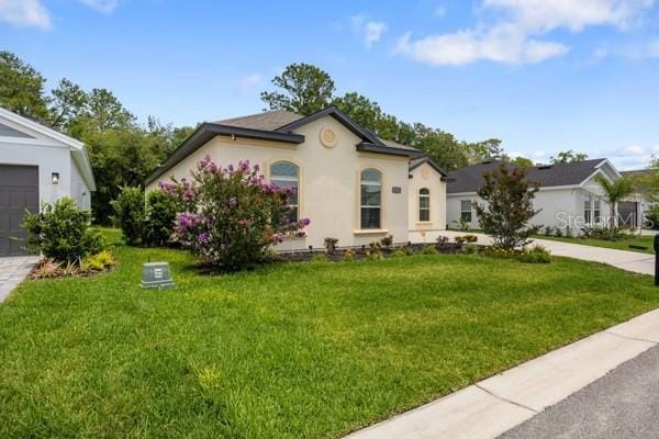 6235 SW 95th Pl, Ocala, FL 34476 - view of front of home with a front lawn, stucco siding, and driveway
