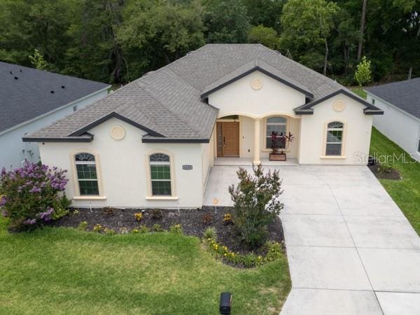 6235 SW 95th Pl, Ocala, FL 34476 - french country style house featuring roof with shingles, concrete driveway, and a front yard