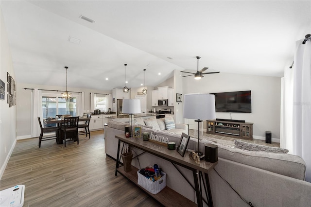 7442 SW 129th Ln, Ocala, FL 34473 - living room with a ceiling fan, vaulted ceiling, light wood-type flooring, baseboards, and a chandelier