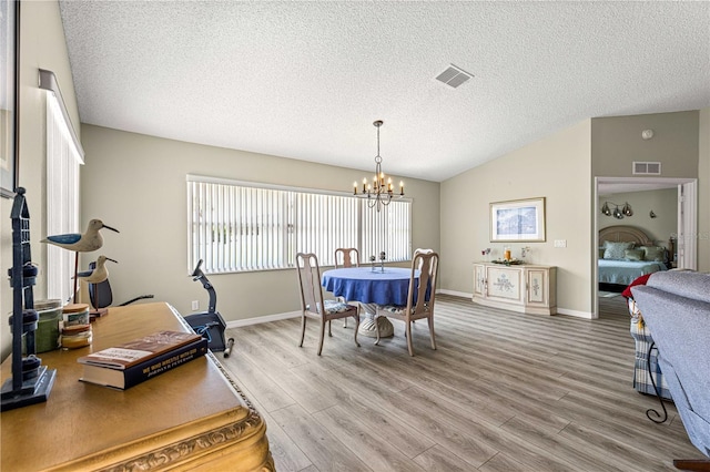 9266 SW 91st Cir, Ocala, FL 34481 - dining space featuring light wood-style floors, a chandelier, a textured ceiling, vaulted ceiling, and baseboards